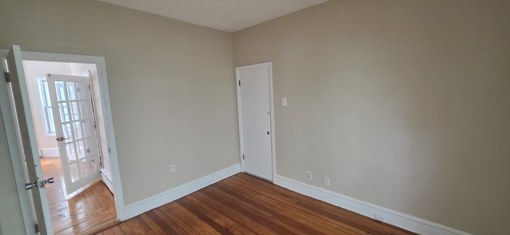 105 6th Street, Unit 1 Fall River, MA 02721 - Photo 5 of 8 a view of an empty room with wooden floor and a window