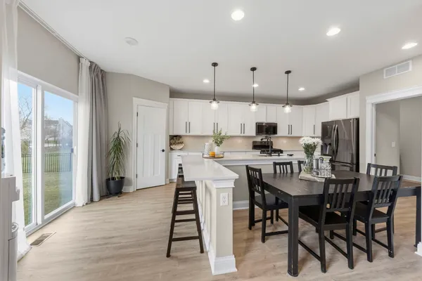 a kitchen with stainless steel appliances kitchen island granite countertop a sink a stove a dining table and chairs