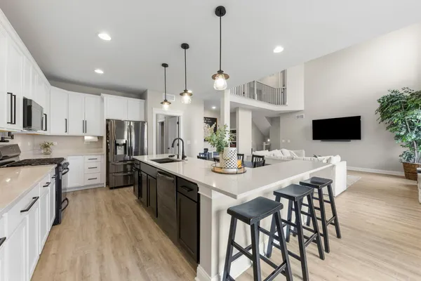 a kitchen with stainless steel appliances kitchen island granite countertop a sink a stove and a wooden floors