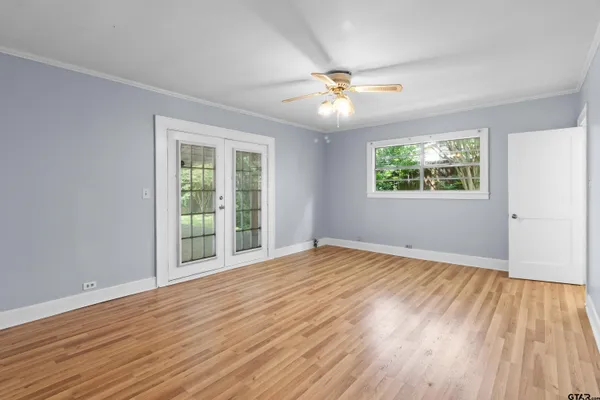 a view of an empty room with wooden floor and a window