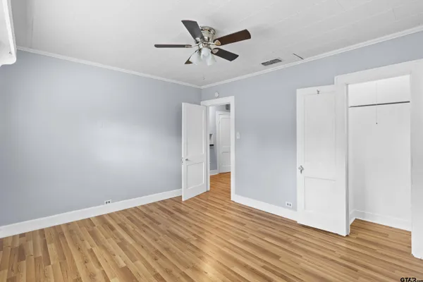 an empty room with wooden floor and a ceiling fan