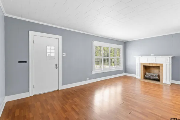 an empty room with wooden floor a fireplace and windows