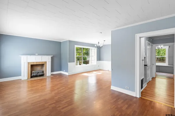 an empty room with wooden floor fireplace and windows