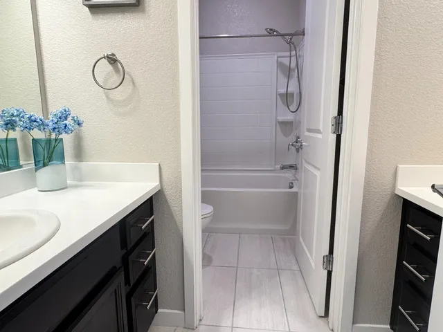 a bathroom with a granite countertop sink a toilet and shower