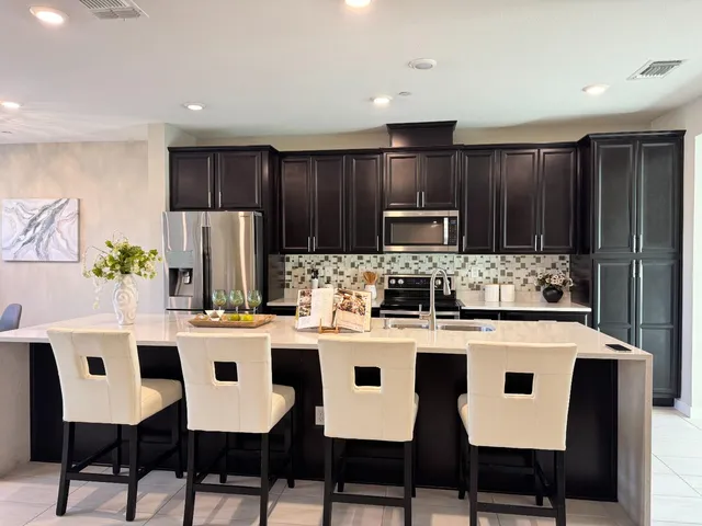 a kitchen with stainless steel appliances a dining table chairs microwave and refrigerator