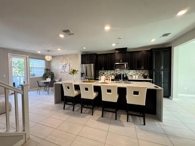 a kitchen with kitchen island granite countertop a dining table chairs and white cabinets