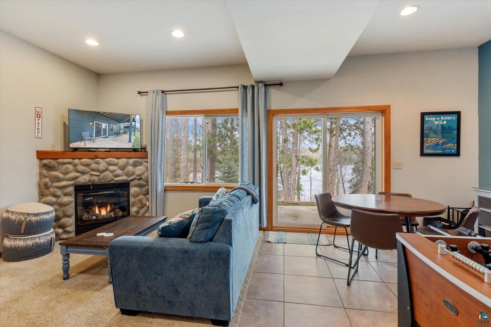 6266 Giants Ridge Road Biwabik, MN 55705 - Photo 16 of 37 Living area featuring a stone fireplace with a wood mantle, recessed lighting, and a sliding glass door to an outdoor area with a lake backdrop