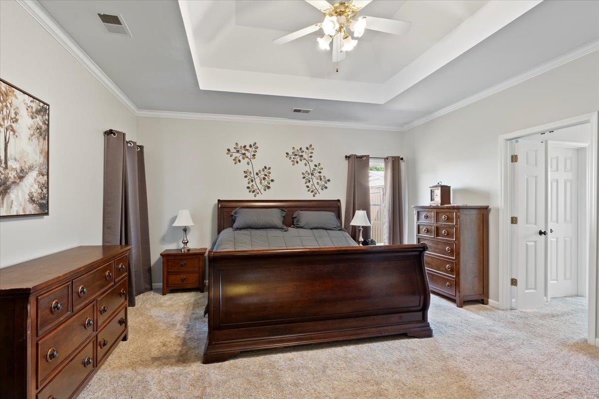 1675 John Ridge Drive Collierville, TN 38017 - Photo 19 of 39 Bedroom featuring a raised ceiling, light colored carpet, ornamental molding, and a ceiling fan