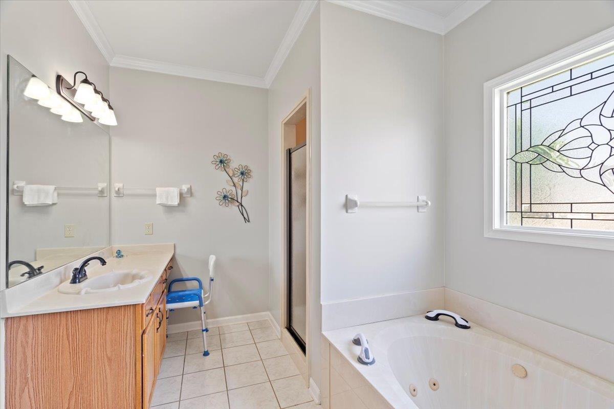 1675 John Ridge Drive Collierville, TN 38017 - Photo 22 of 39 Bathroom with double vanity, a jetted tub, a shower stall, tile patterned floors, and ornamental molding