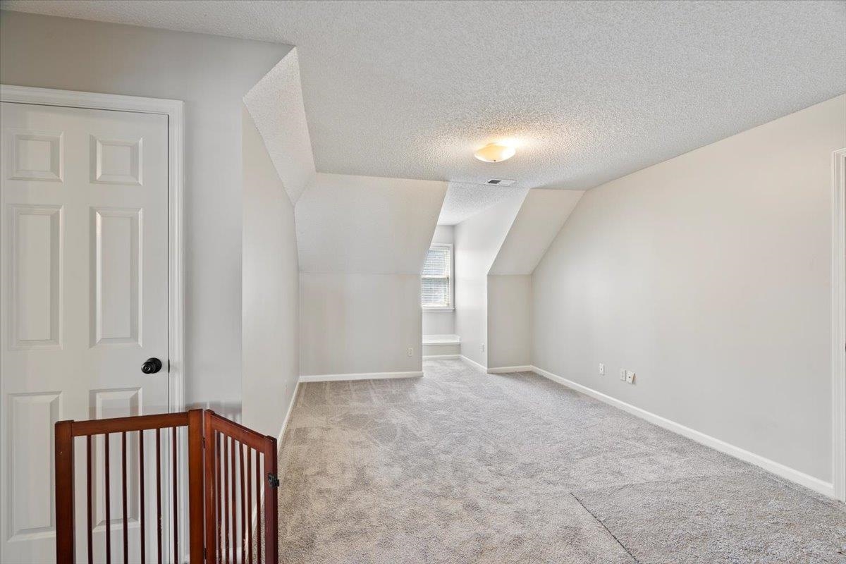 1675 John Ridge Drive Collierville, TN 38017 - Photo 25 of 39 Additional living space with carpet, baseboards, vaulted ceiling, and a textured ceiling