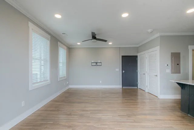 a view of an empty room with wooden floor and a window