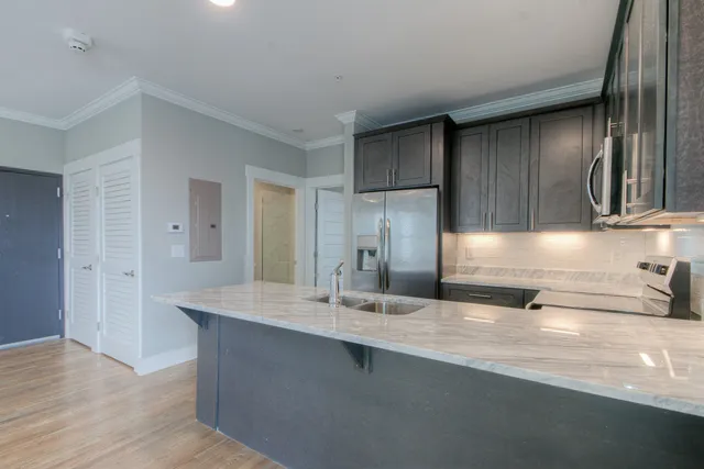 a view of a kitchen counter top space with stainless steel appliances granite countertop wooden floor and a sink