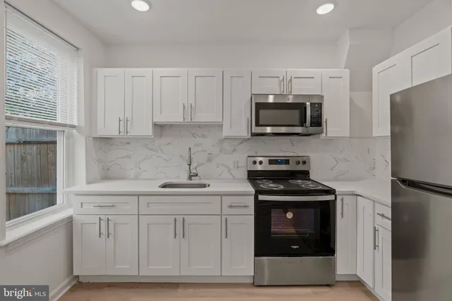 a kitchen with white cabinets and stainless steel appliances