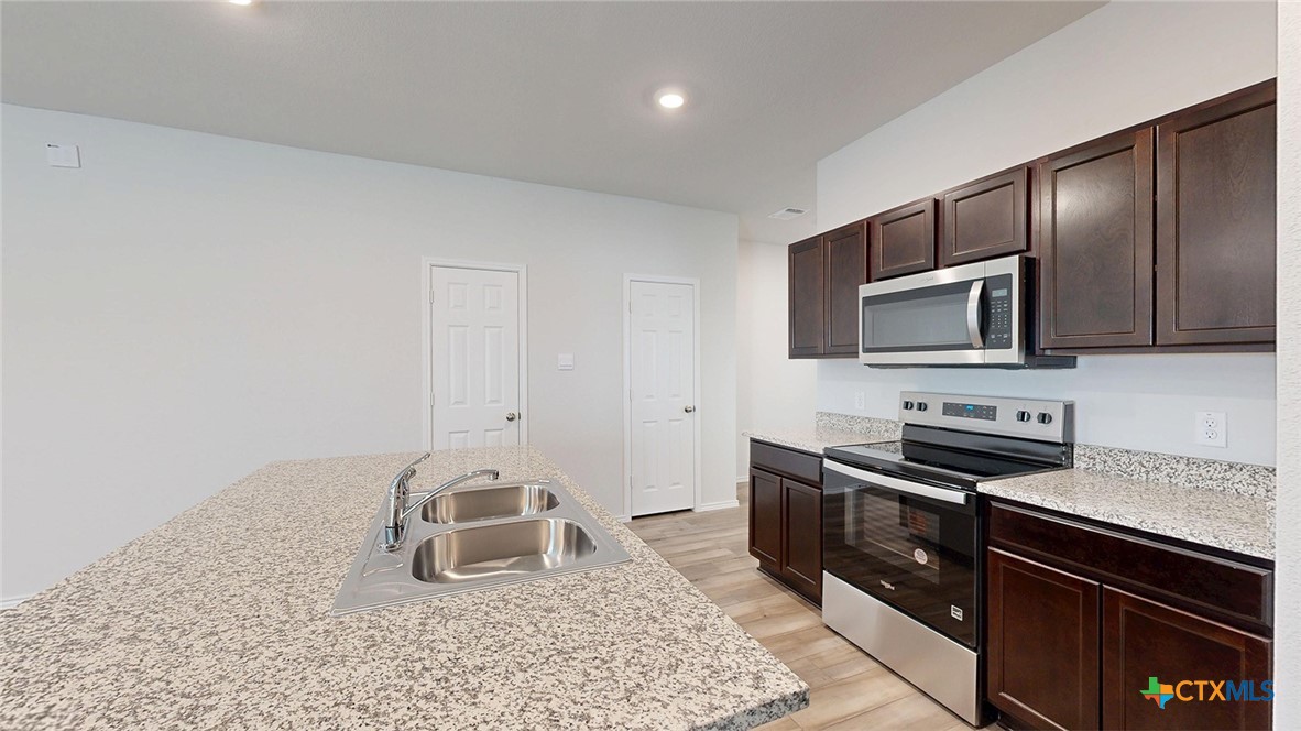 1302 Merritt Road Temple, TX 76504 - Photo 4 of 31 a kitchen with granite countertop a stove and a sink