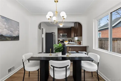 a dining room with wooden floor a chandelier a wooden table and chairs