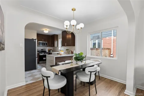 a dining room with wooden floor a chandelier a wooden table and chairs