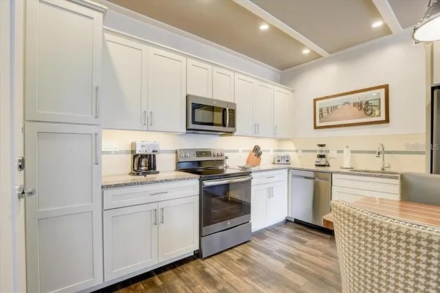 a kitchen with stainless steel appliances granite countertop a stove a sink and white cabinets