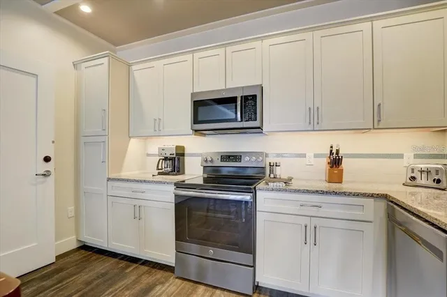 a kitchen with granite countertop white cabinets and stainless steel appliances