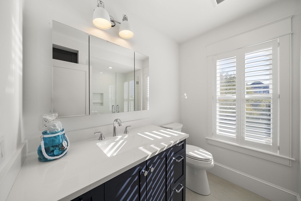 74-76 Butler Road Quincy, MA 02169 - Photo 21 of 41 a bathroom with a granite countertop sink a toilet and a mirror
