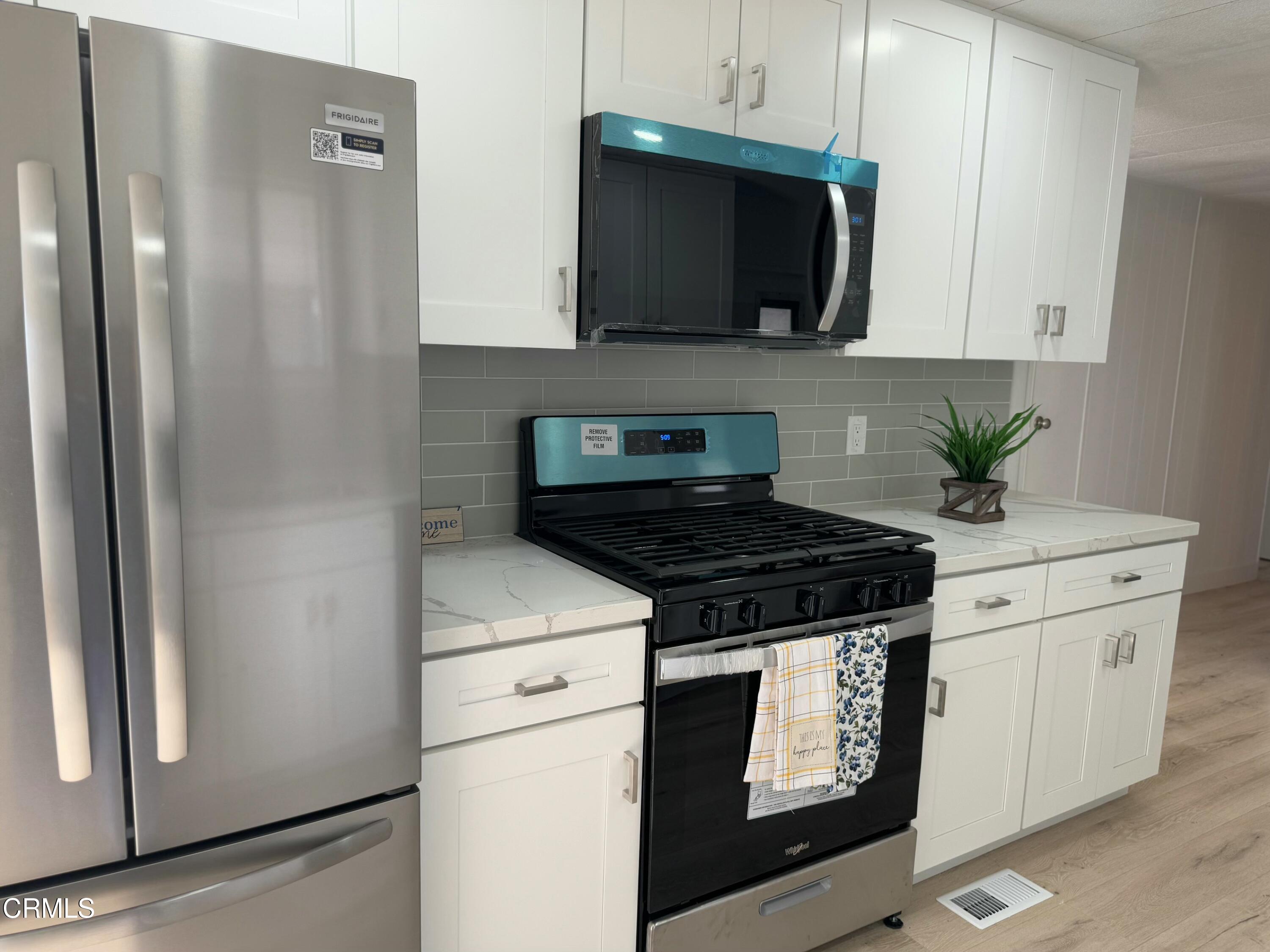 a kitchen with stainless steel appliances white cabinets and a stove top oven