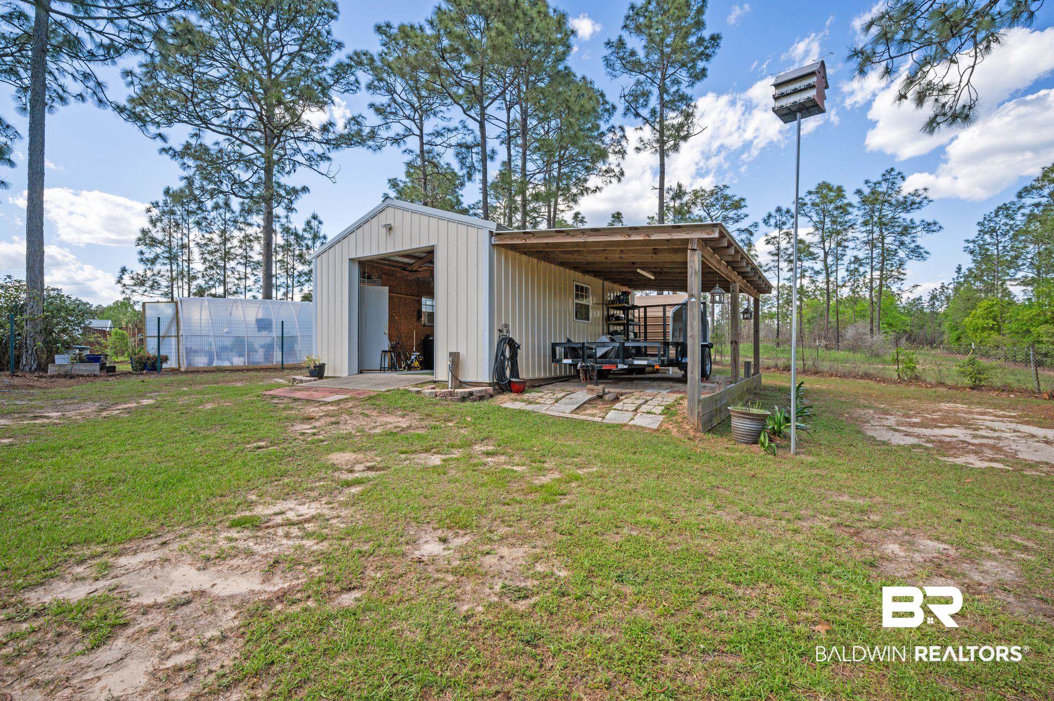 3100 Radcliff Road Saraland, AL 36571 - Photo 48 of 65 Back of property with board and batten siding, an outbuilding, an outdoor structure, and a yard