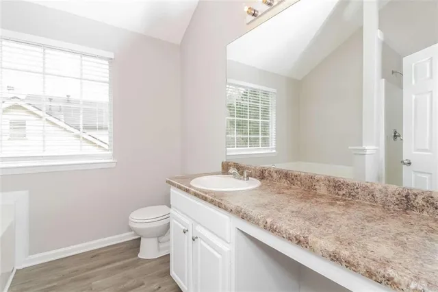 a bathroom with a granite countertop sink a toilet and a window
