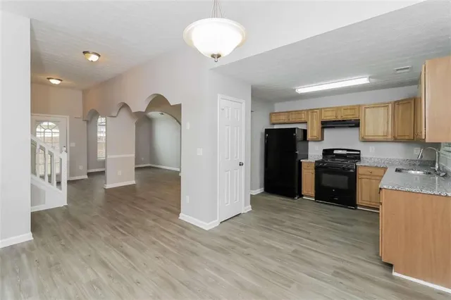 a kitchen with granite countertop a refrigerator and a stove top oven