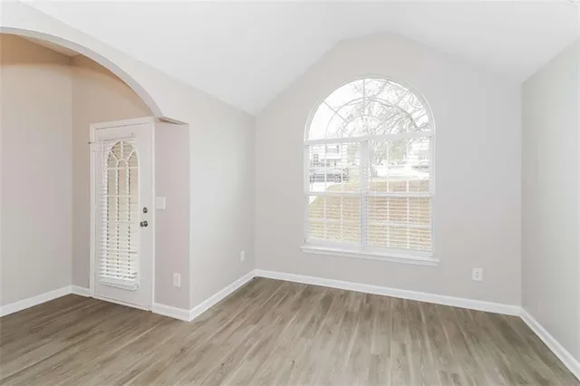 an empty room with wooden floor windows and exposed bricks