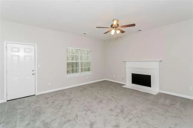 an empty room with windows and fireplace