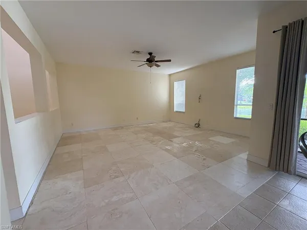 an empty room with windows and fan