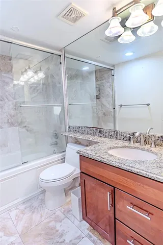 a bathroom with a granite countertop sink a toilet a mirror and bathtub