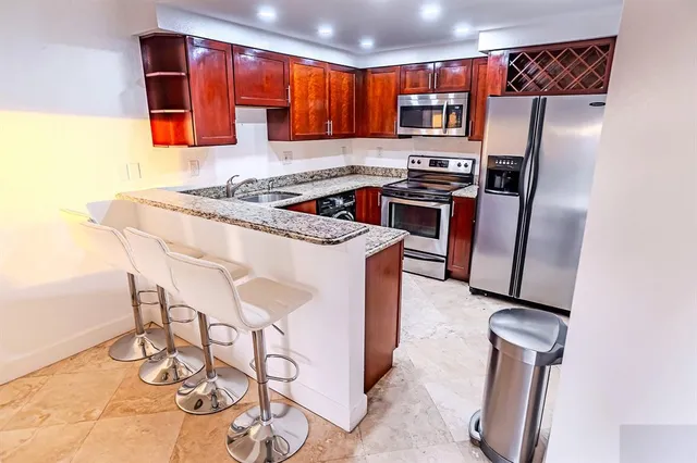 a kitchen with stainless steel appliances granite countertop a refrigerator sink and stove