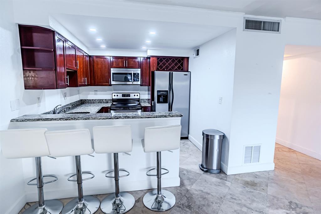 2900 Northeast 30th Street, Unit 3F Fort Lauderdale, FL 33306 - Photo 5 of 30 a kitchen with stainless steel appliances kitchen island granite countertop a sink and cabinets