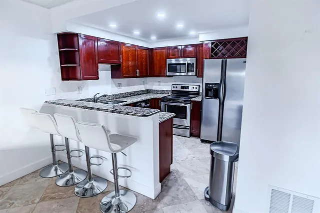 a kitchen with stainless steel appliances granite countertop a stove top oven a sink and a refrigerator