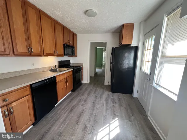 a kitchen with stainless steel appliances granite countertop a refrigerator a sink dishwasher a stove and a refrigerator with wooden floor