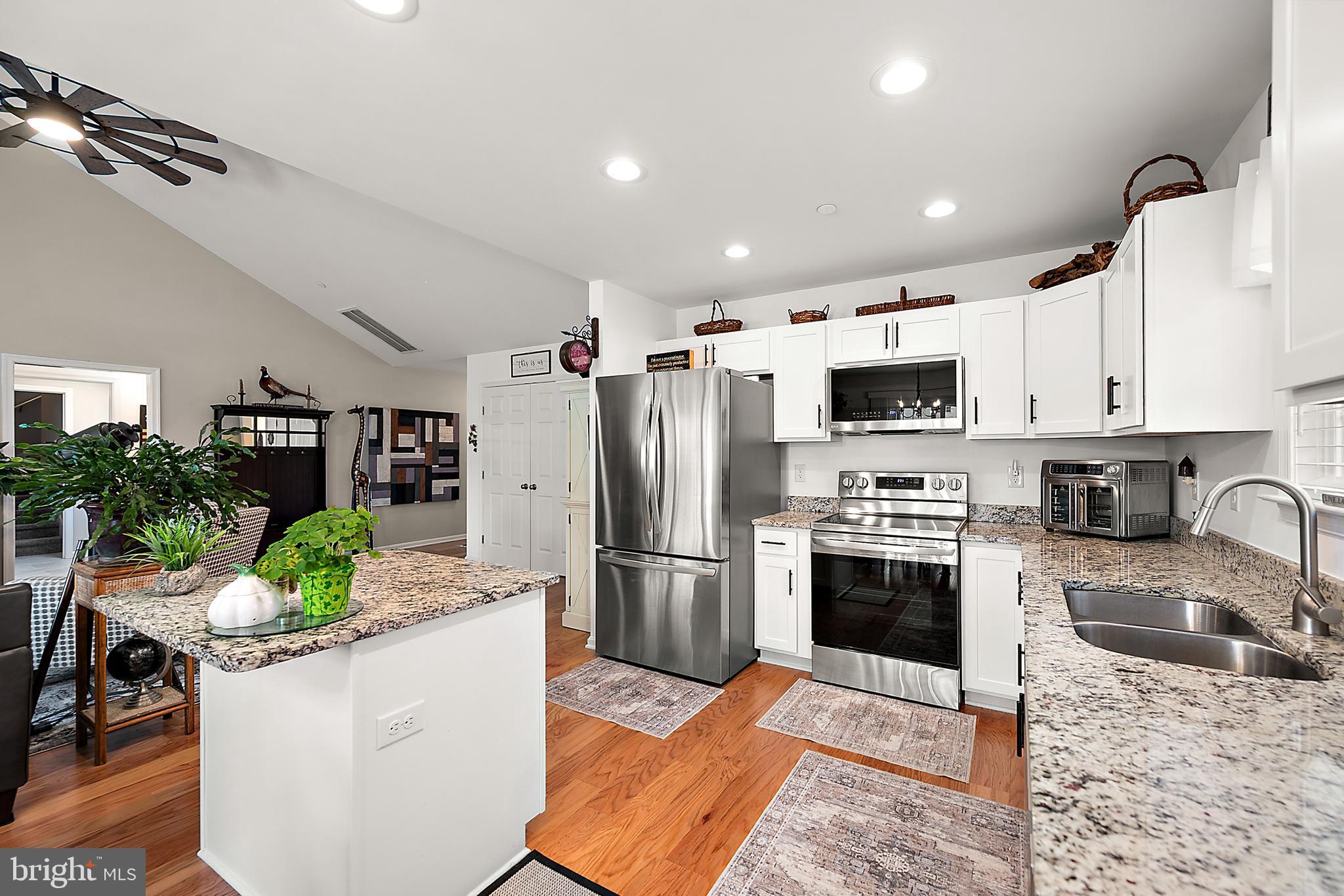6098 Tarry Town Road Salisbury, MD 21801 - Photo 19 of 60 a kitchen with stainless steel appliances kitchen island granite countertop a refrigerator a stove a sink dishwasher and white cabinets with wooden floor