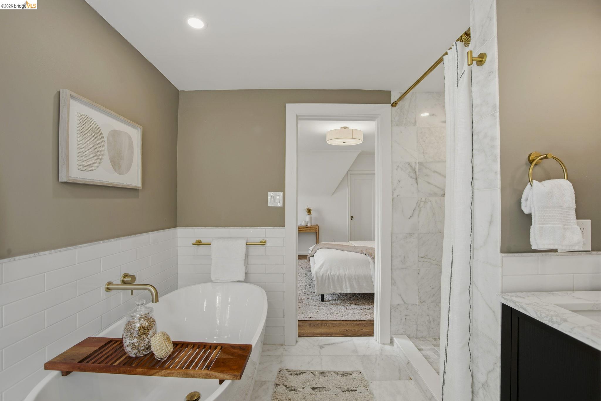 1087 Hubert Road Oakland, CA 94610 - Photo 26 of 67 Freestanding soaking tub with gold-finish fixtures and white subway tile wainscoting