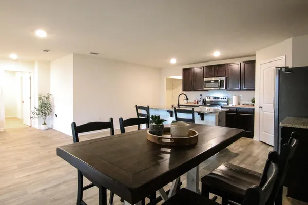 a view of kitchen with refrigerator stove dining table and chairs