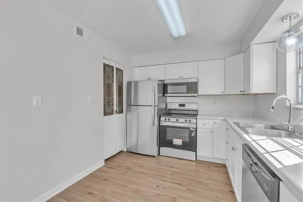 a kitchen with stainless steel appliances granite countertop a refrigerator stove a sink and dishwasher with wooden floor