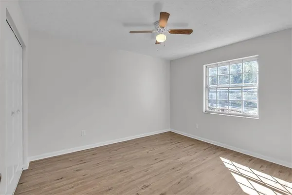 an empty room with wooden floor fan and windows