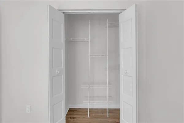 an empty room with wooden floor chandelier fan and windows