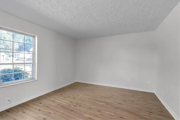 a view of an empty room with wooden floor and a window