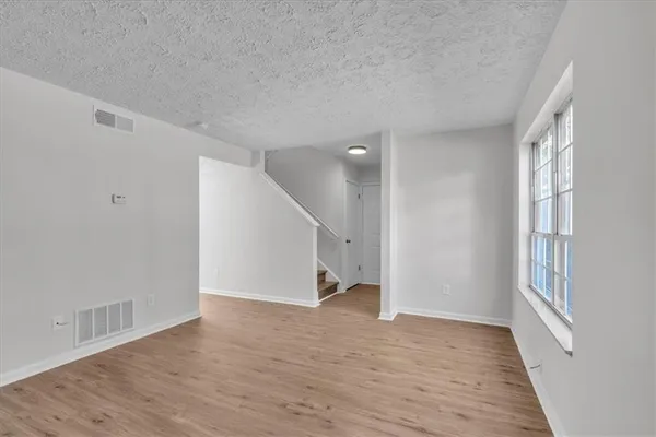 an empty room with wooden floor and windows