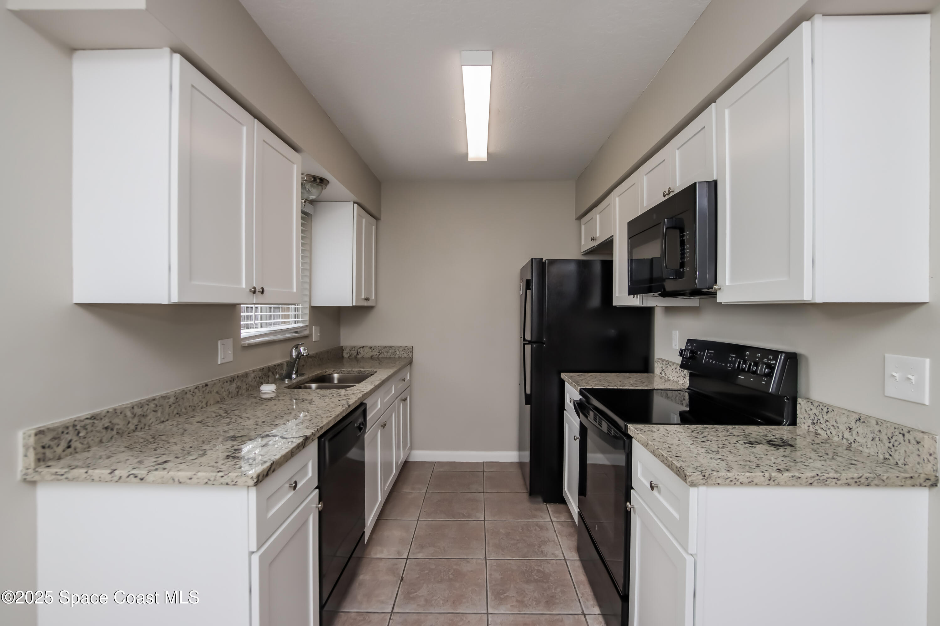 1130 Emerald Road Southeast Palm Bay, FL 32909 - Photo 5 of 16 a kitchen with stainless steel appliances granite countertop a stove top oven a sink a refrigerator and white cabinets