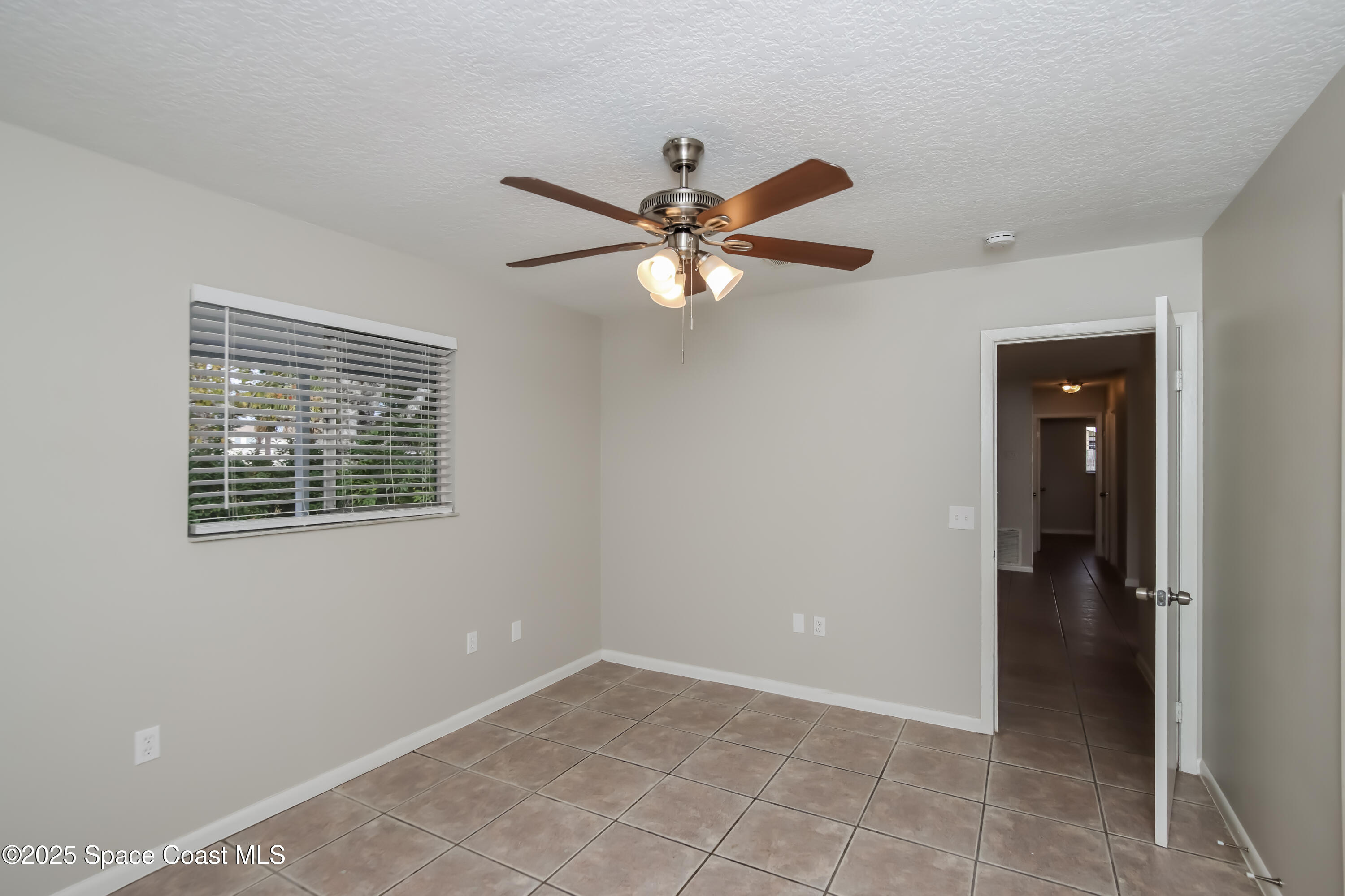 1130 Emerald Road Southeast Palm Bay, FL 32909 - Photo 8 of 16 a view of an empty room with a ceiling fan and a window