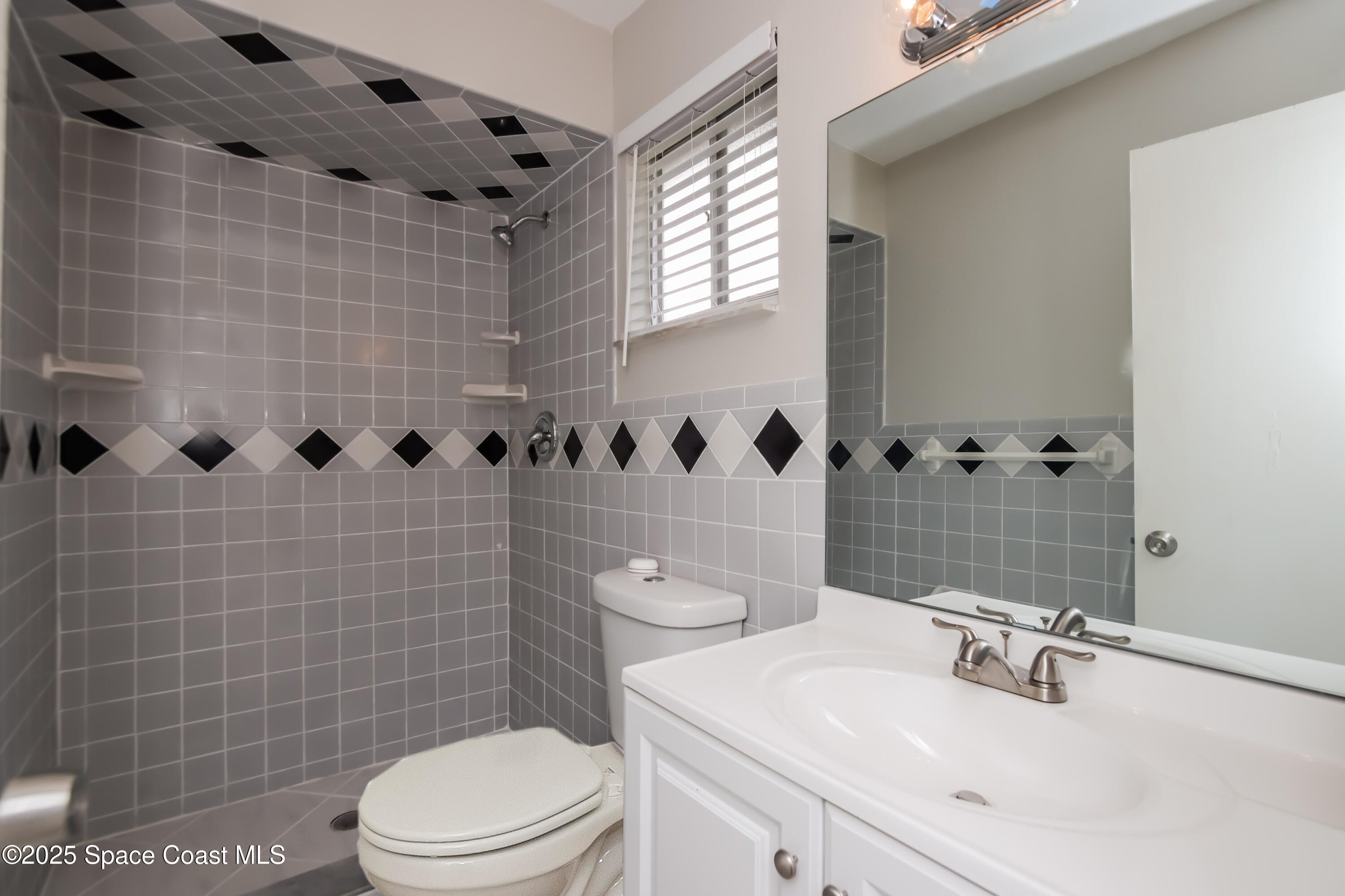 1130 Emerald Road Southeast Palm Bay, FL 32909 - Photo 9 of 16 a bathroom with a sink a toilet and shower curtain