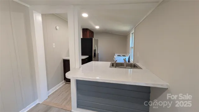 a room with kitchen island a sink and a refrigerator