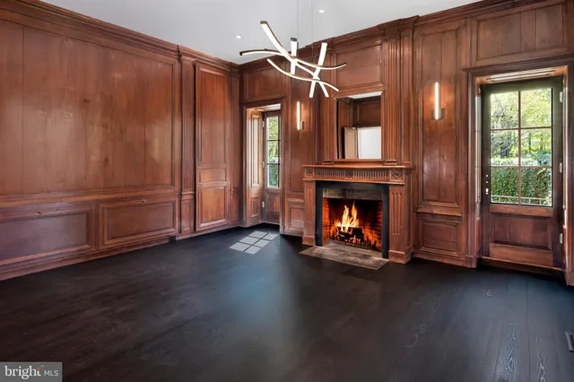a view of an empty room with wooden floor fireplace and windows
