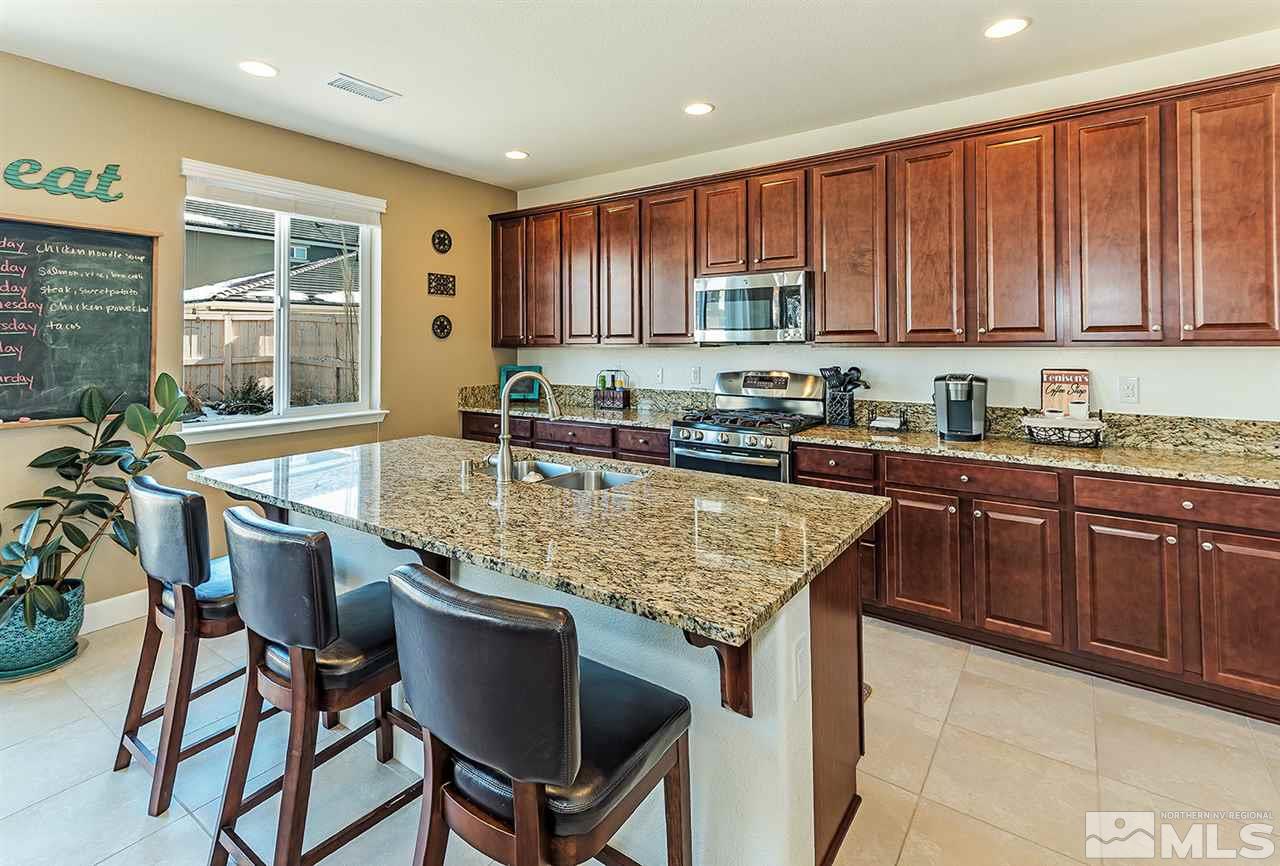 10350 Culiacan Pass Trail Reno, NV 89521 - Photo 6 of 20 a kitchen with kitchen island granite countertop a table chairs sink and cabinets
