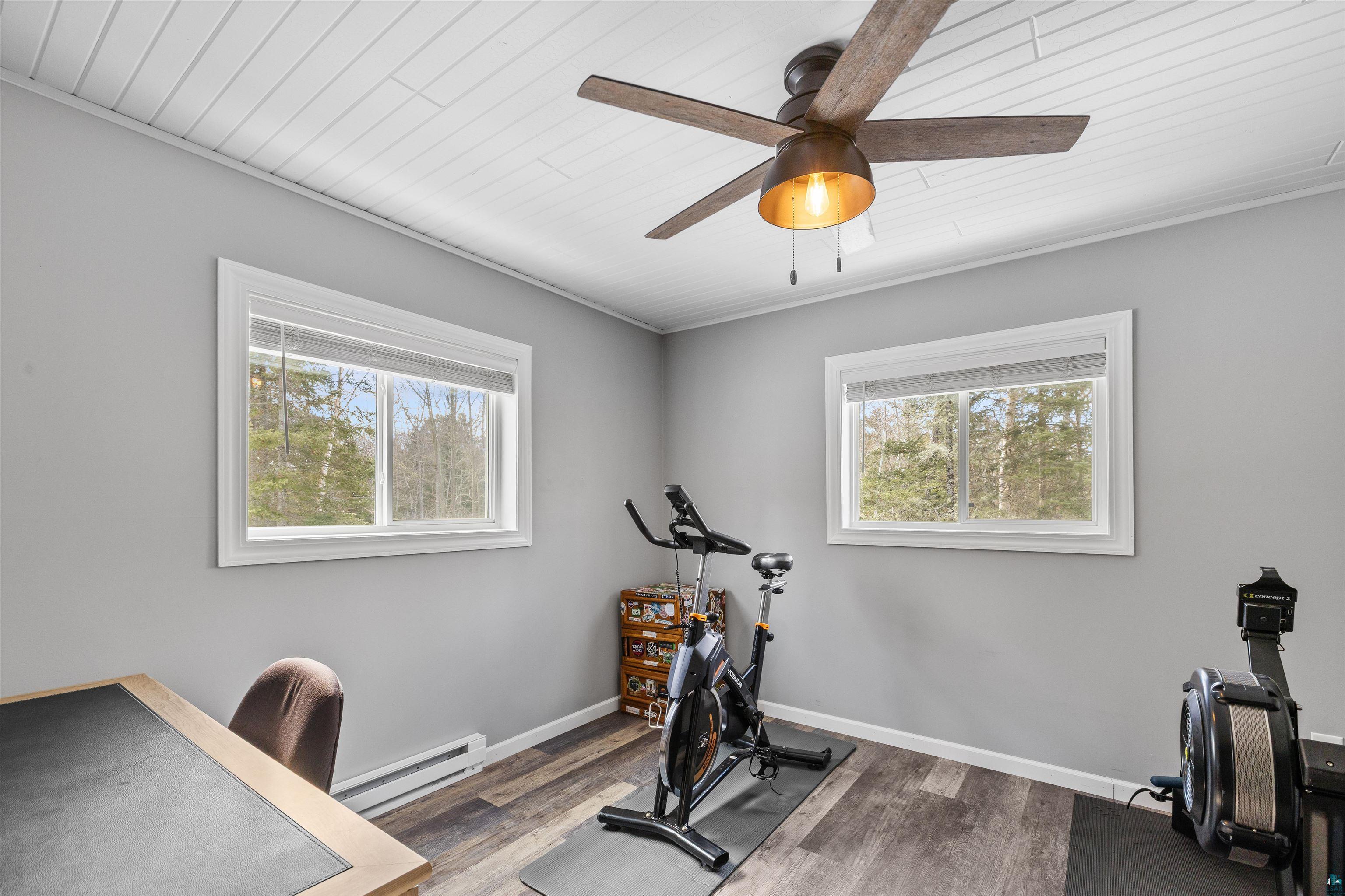 13462 Villa Road Ely, MN 55731 - Photo 19 of 68 Upper level bedroom being used as an exercise area featuring baseboard heating, Lifeproof flooring, wooden ceiling, healthy amount of natural light, and ceiling fan